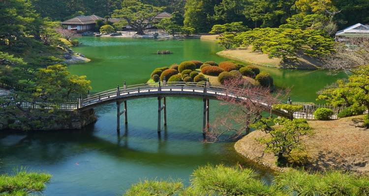 Traditional Japanese garden with a lake and bridge.