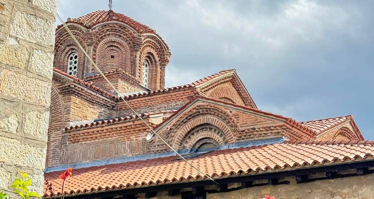 Traditional church with red-domed roof against a cloudy sky