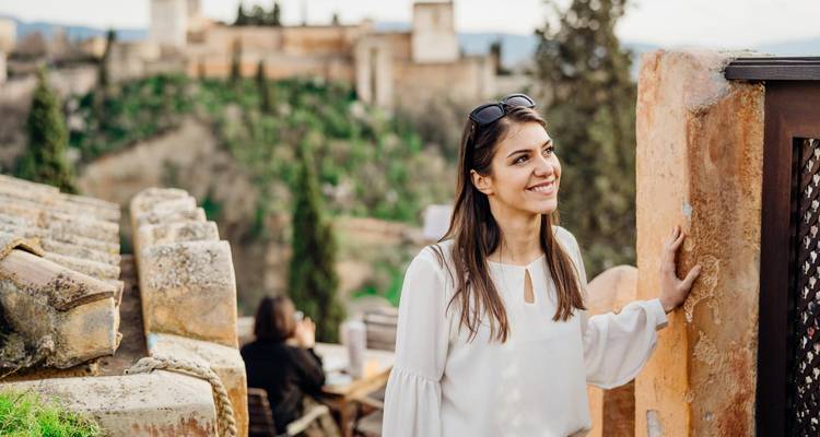 Woman smiling at a scenic view with historic architecture.