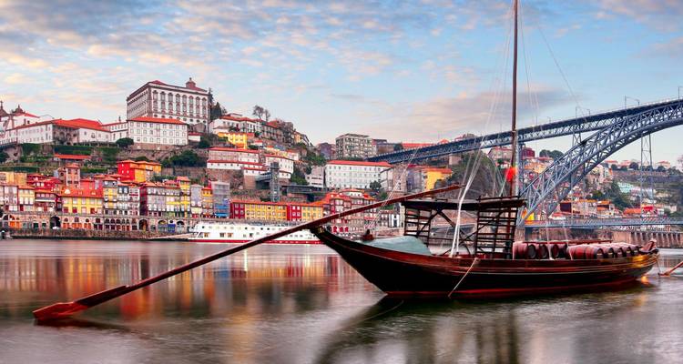 Bateau traditionnel en bois sur une rivière avec un pont et des bâtiments colorés.