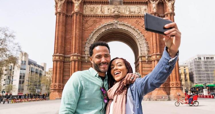 Pareja tomándose una selfie frente a un gran arco.