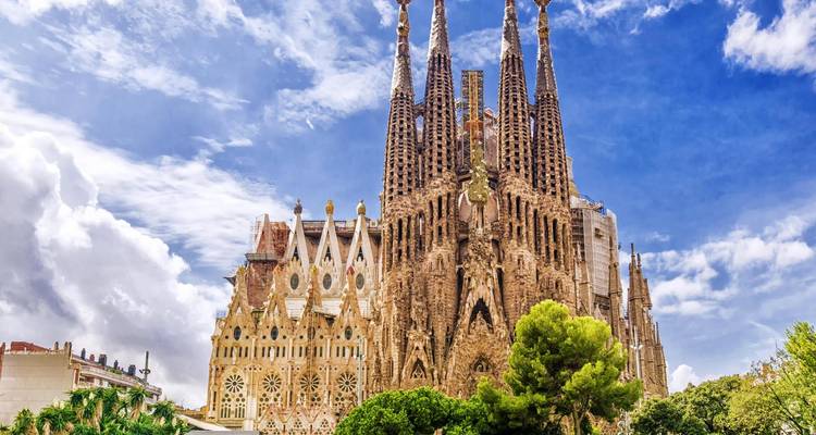 Sagrada Familia con cielo azul y árboles.