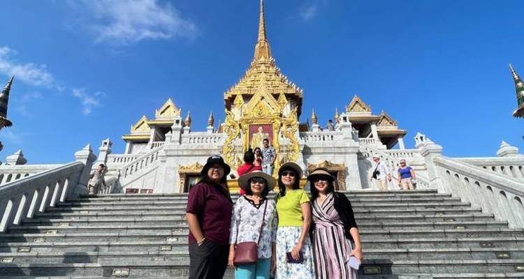Groupe de personnes posant sur les marches d'un grand temple sous un ciel bleu dégagé.