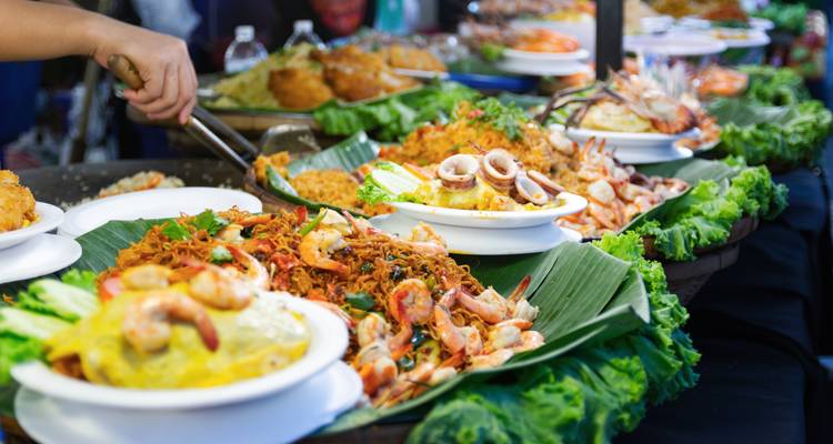 Une variété de plats de cuisine de rue thaïlandaise disposés sur une table avec des légumes verts et des fruits de mer.