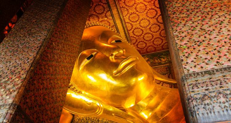 La statue du Bouddha couché aux décorations complexes et aux couleurs dorées.