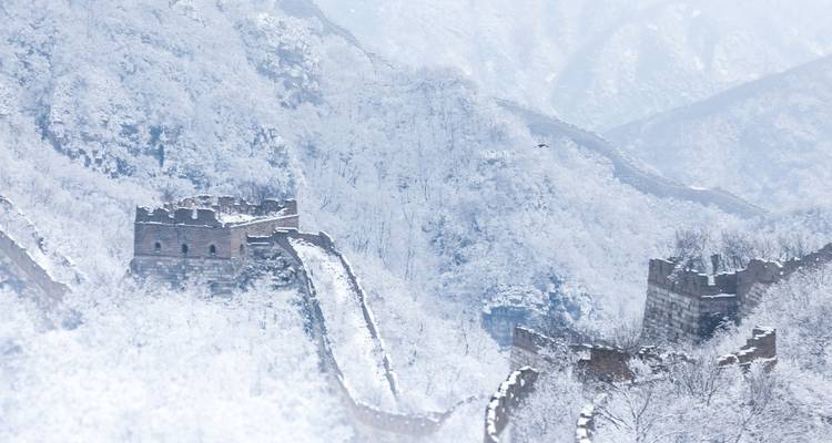 Besneeuwde Chinese Muur in een bergachtig landschap.