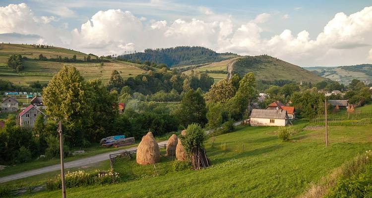 Un paysage rural avec des meules de foin et des collines sous un ciel nuageux.