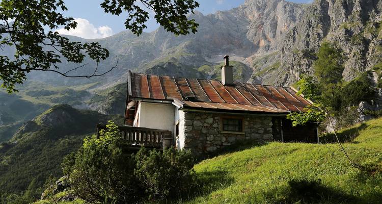 Une cabane rustique avec un toit en métal située dans un décor de montagne.