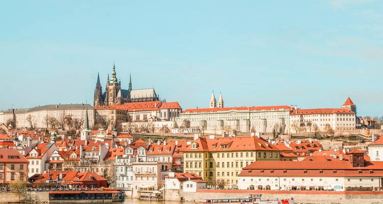 Vue du château de Prague avec des toits rouges et la rivière.