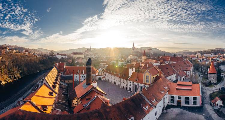 Vue panoramique d'une ville avec des toits rouges sous un vaste ciel.