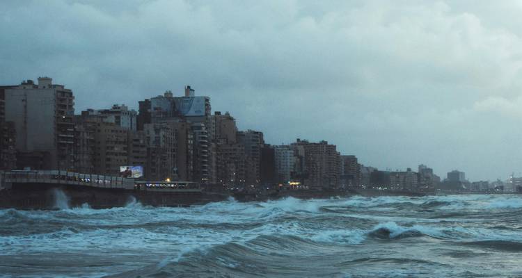 Kuststedelijk landschap met golven die tegen een zeedijk beuken.