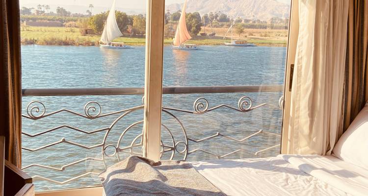 Uitzicht vanuit een raam op een rivier met zeilboten.