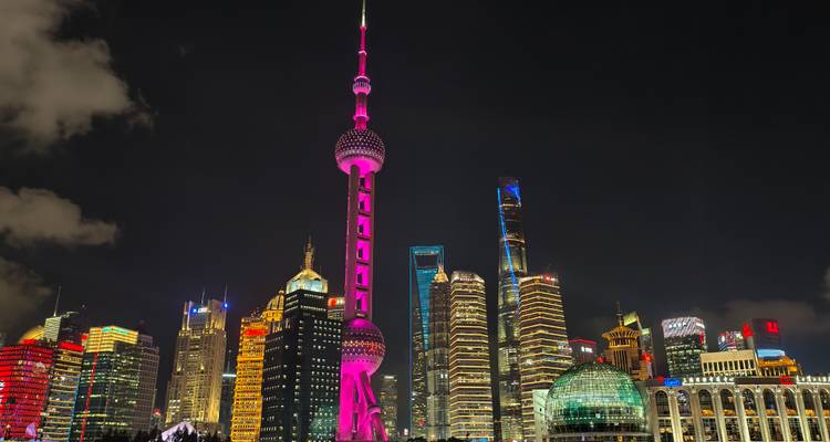Paysage urbain de nuit avec une tour illuminée proéminente et des gratte-ciel.