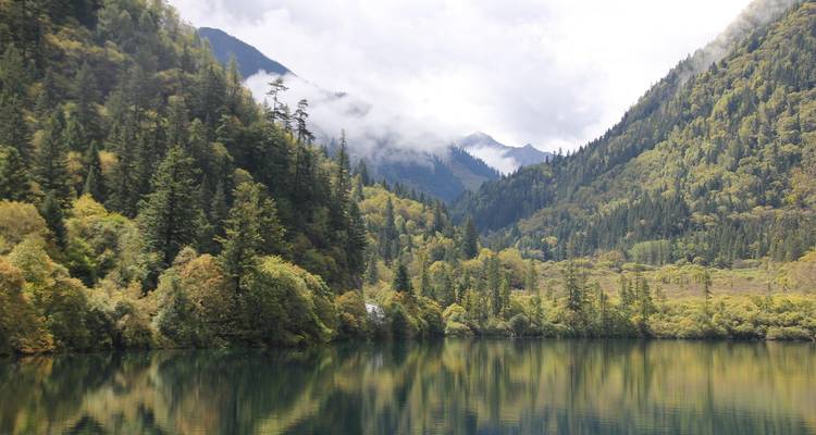 Lac serein entouré de montagnes boisées.