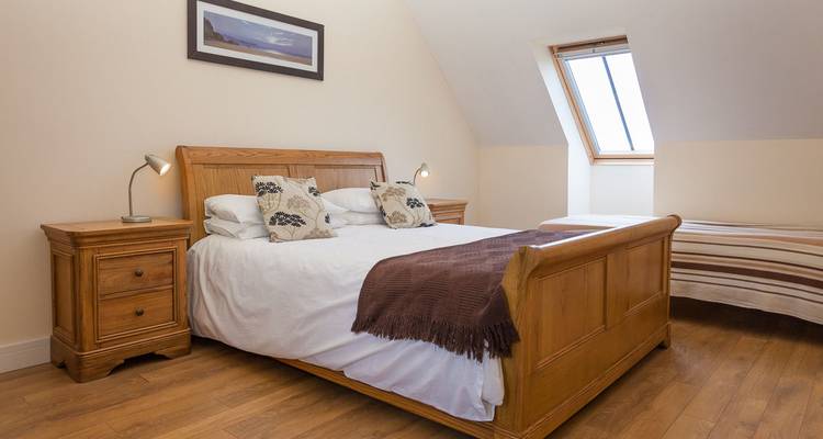 Chambre d'hôtel avec un lit en bois et une fenêtre de toit.
