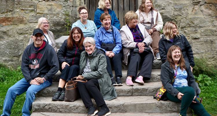 Groupe de personnes assises sur des marches de pierre devant un bâtiment historique.