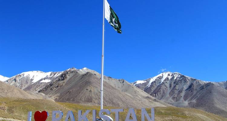 Bergige Landschaft mit einem hohen Fahnenmast und pakistanischer Flagge.