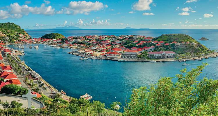 Colorful seaside town with red roofs and boats in the harbor.
