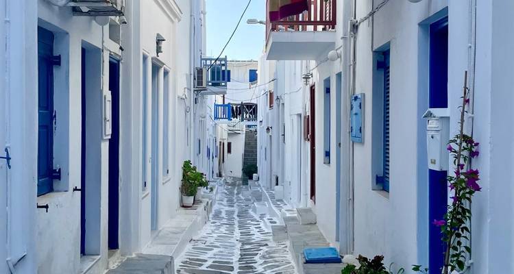 Une rue étroite avec des bâtiments bleus et blancs, typique de l'architecture grecque.
