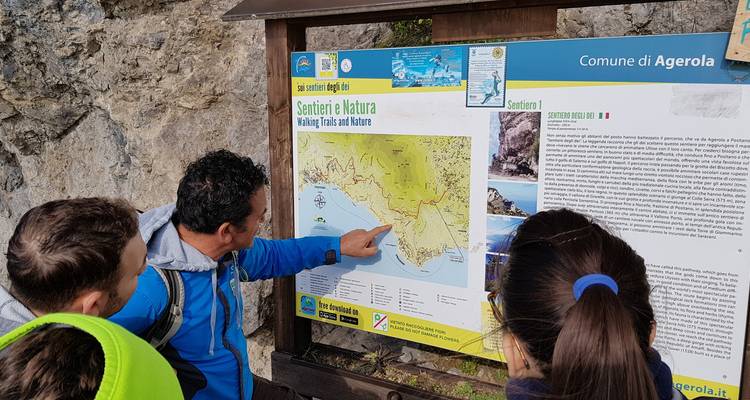 Un guide montrant une carte à un groupe de touristes sur un sentier de randonnée.