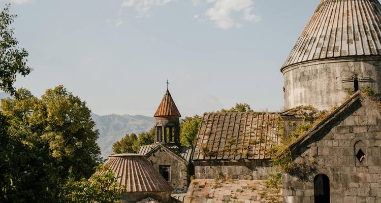 Ancienne église de pierre avec des dômes entourée d'arbres.