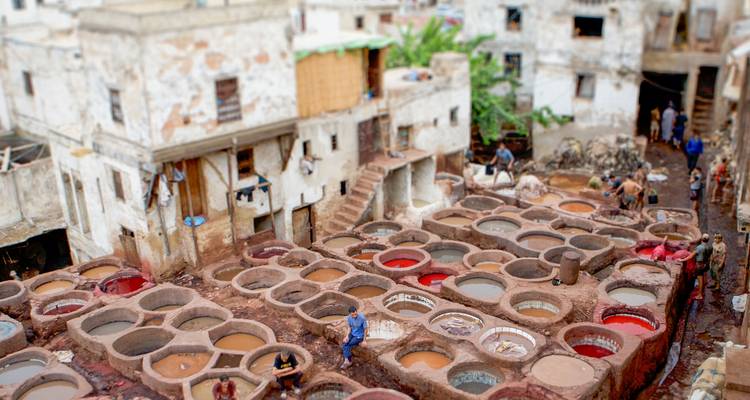 Ouvriers de la tannerie de Fès avec des cuves de teinture de différentes couleurs.