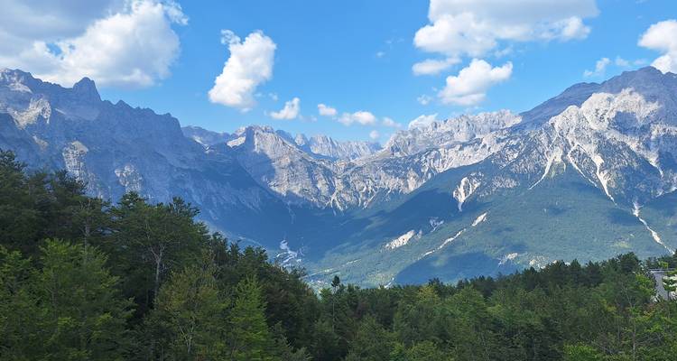 Mountainous landscape with forested areas and steep peaks.