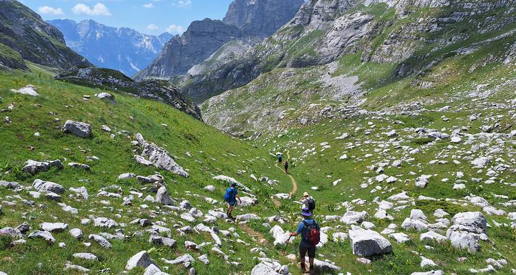 Hikers walking along a rocky path in a mountainous terrain.