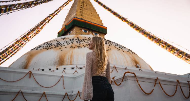 Persona admirando la Estupa de Boudhanath con banderas de oración.