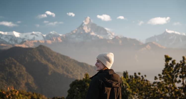 Persona contemplando montañas cubiertas de nieve bajo un cielo despejado.