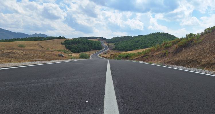 Vista de ángulo bajo a lo largo de un camino rural recién pavimentado que se extiende a través de colinas onduladas