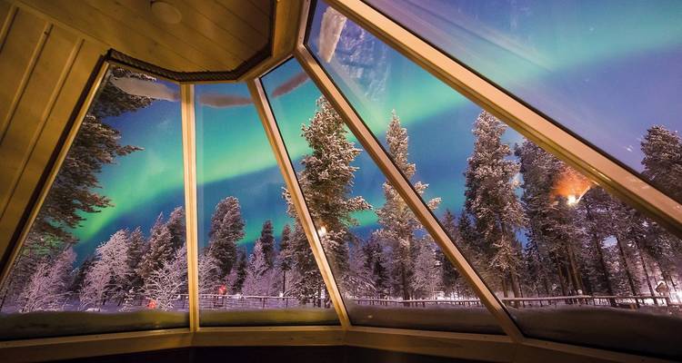 Vue des aurores boréales depuis l'intérieur d'un igloo en verre.