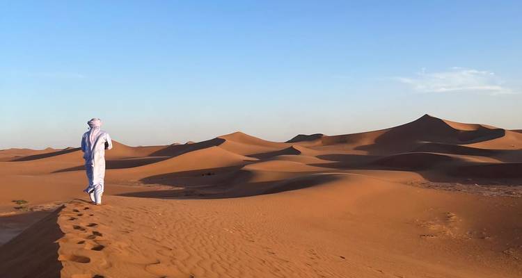 Personne marchant le long de la crête d'une dune de sable dans le désert.