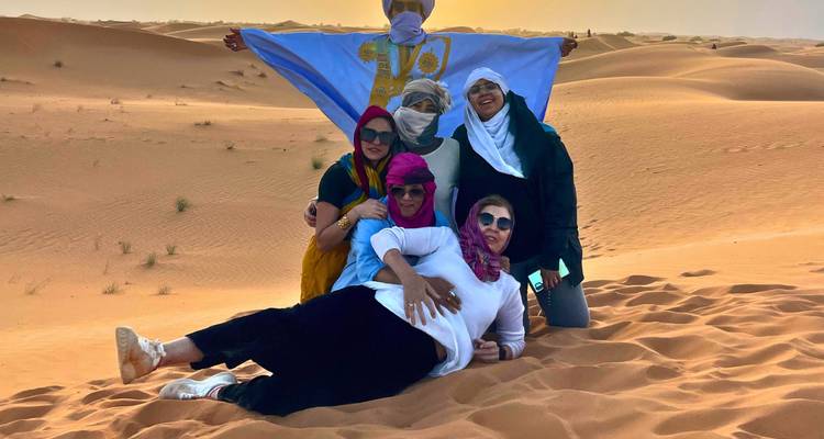 Grupo de personas vestidas con bufandas y atuendo tradicional en el desierto.