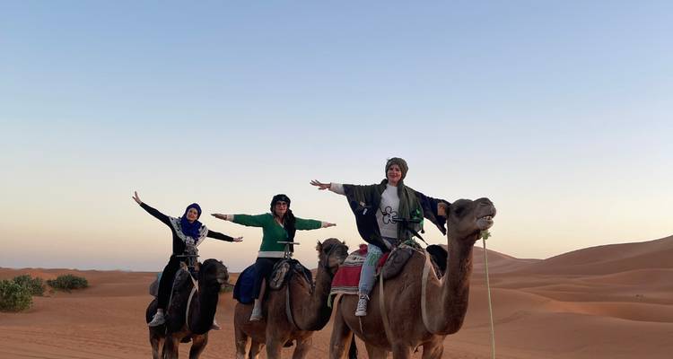 Trois personnes sur des chameaux posant joyeusement.