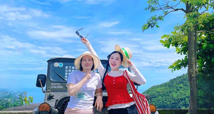 Two women posing with a jeep against a scenic mountain backdrop.