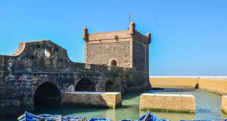 Seaside fortress with moored boats at the waterfront.