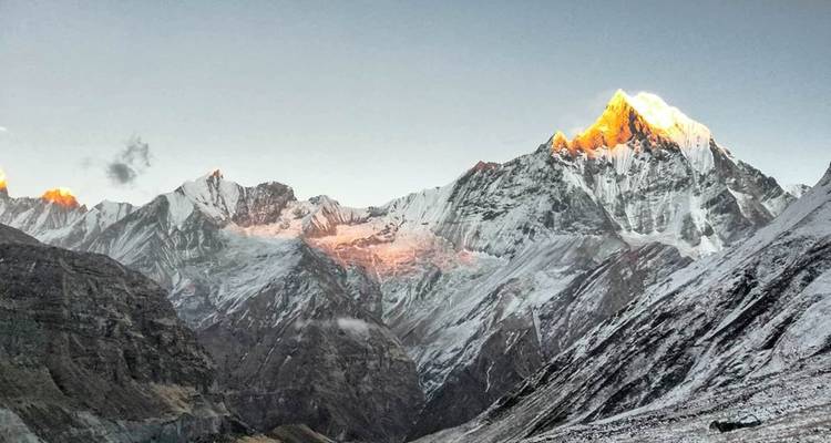 Chaîne de montagnes des Annapurna avec la lumière dorée du soleil sur les sommets.