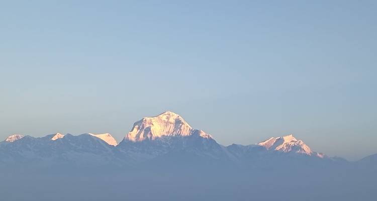 Besneeuwde Himalaya-toppen gloeien roze in het vroege ochtendlicht tegen een heldere hemel.
