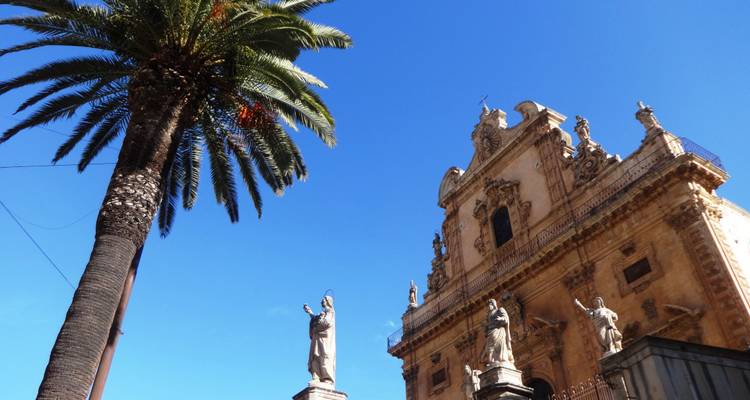Primer plano de la fachada ornamentada de una iglesia con palmeras.