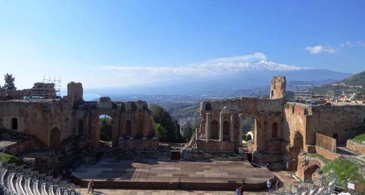 Ruinas de un antiguo teatro con un telón de fondo montañoso.