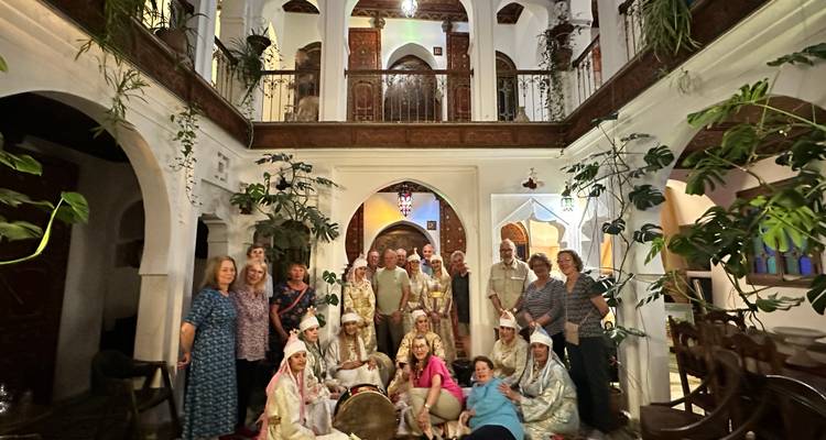 Groupe de personnes en tenue traditionnelle dans un intérieur orné.