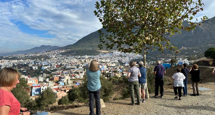 Des touristes observant un paysage urbain avec des montagnes en arrière-plan.