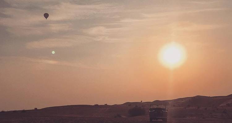 Paysage désertique avec une montgolfière et un coucher de soleil.