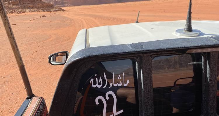 Partie d'un véhicule avec du texte arabe sur fond de désert.