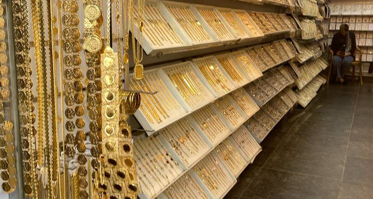 Des bijoux en or exposés dans une boutique avec une personne assise.