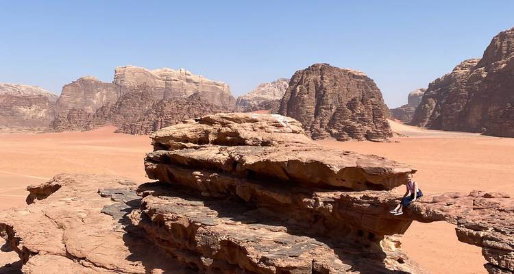 Des personnes assises sur une formation rocheuse dans un paysage désertique.
