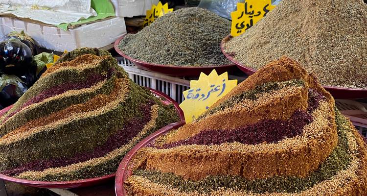 Épices colorées disposées en monticules sur un marché.