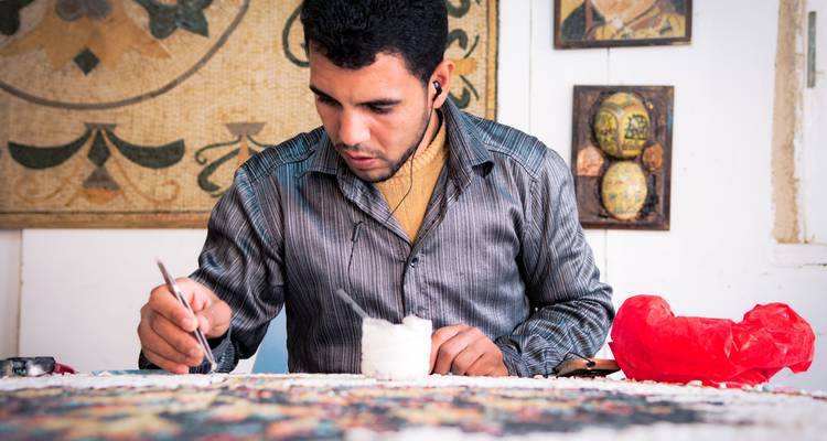 Artiste travaillant sur une mosaïque avec concentration et précision.