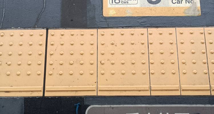 Pavage tactile jaune avec quelques panneaux sur le sol.